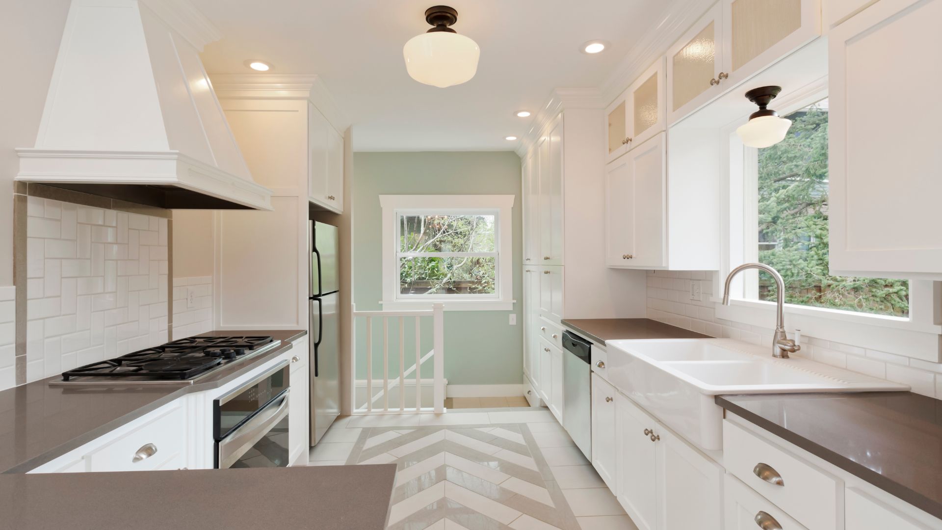 A galley kitchen with white cabinets and stainless steel appliances.