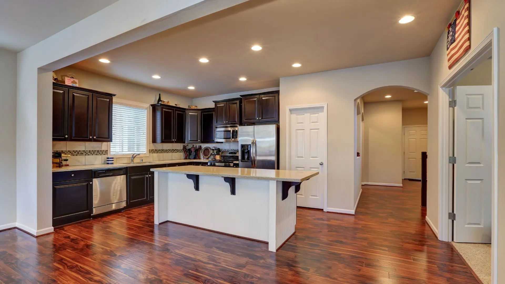 A modern kitchen with dark cabinetry and hardwood floors.