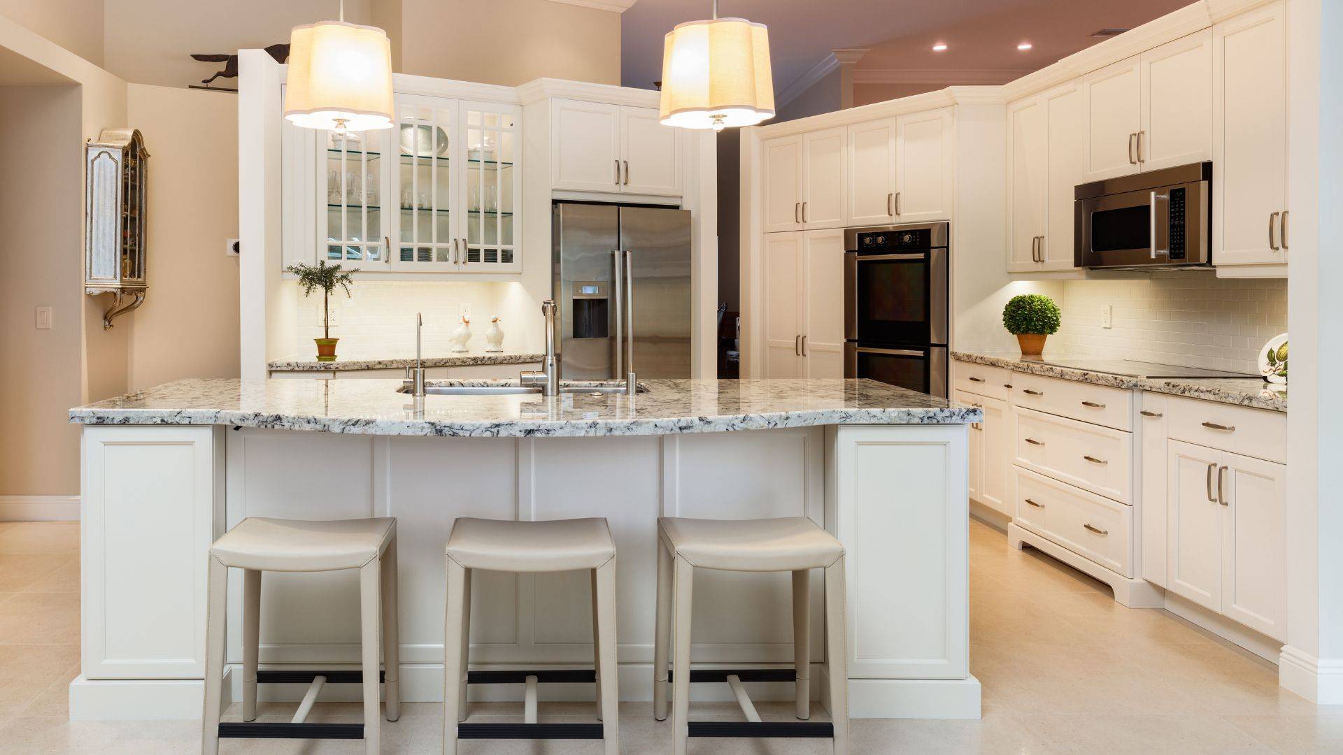 A modern kitchen with white cabinets and marble countertops.