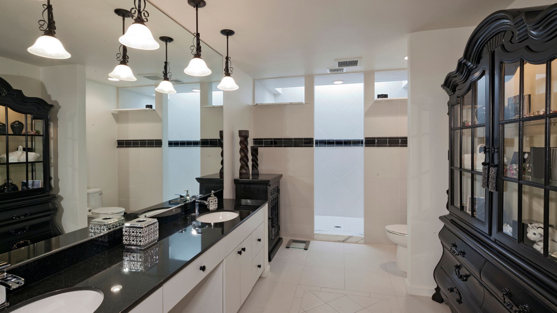 A modern bathroom with white cabinetry and black counters.