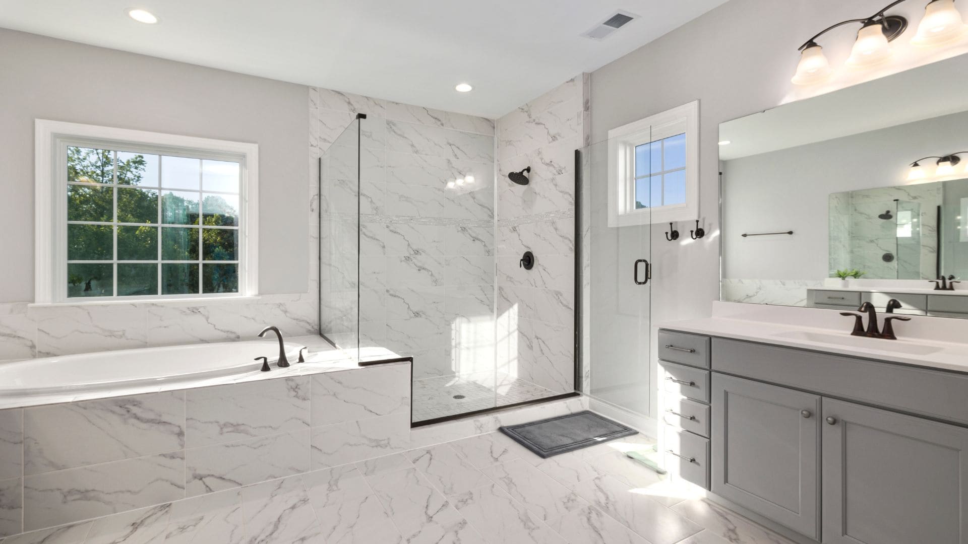 A modern bathroom with a marble shower surround and floor.